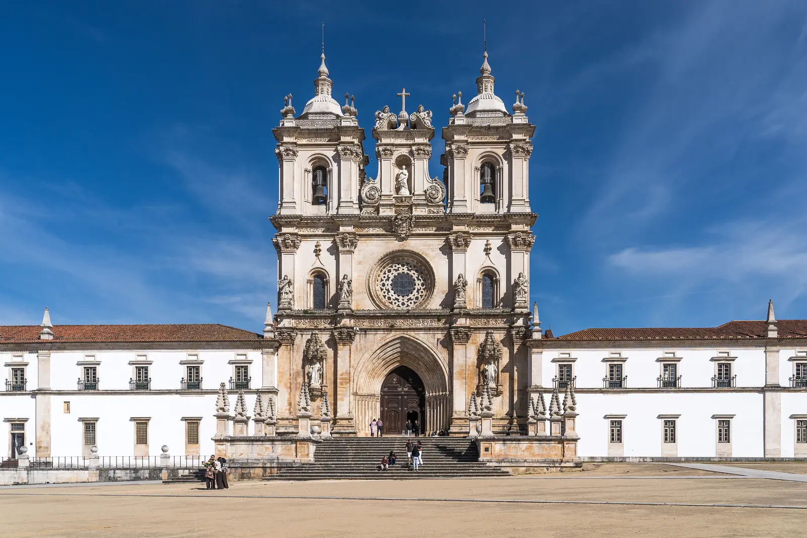 The baroque façade of the Monastery of Alcobaça church under a blue sky