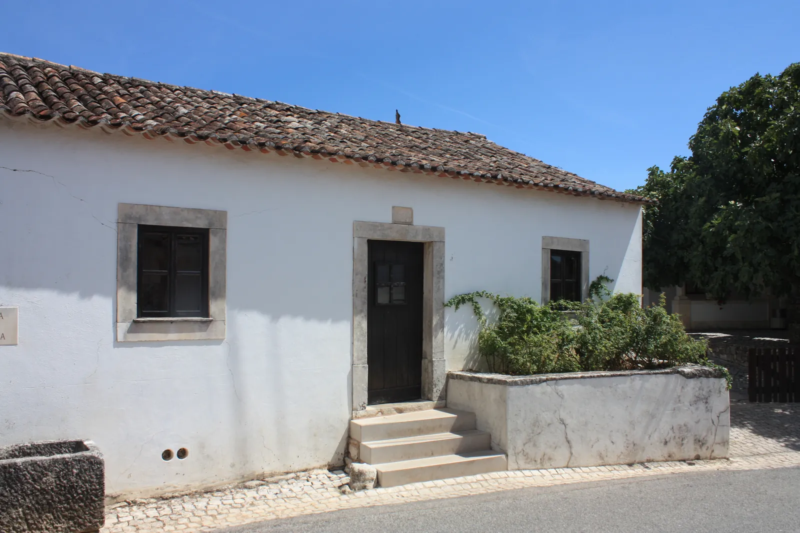 The simple whitewashed family house of Lúcia in Aljustrel, with stone-framed door and windows and a tiled roof