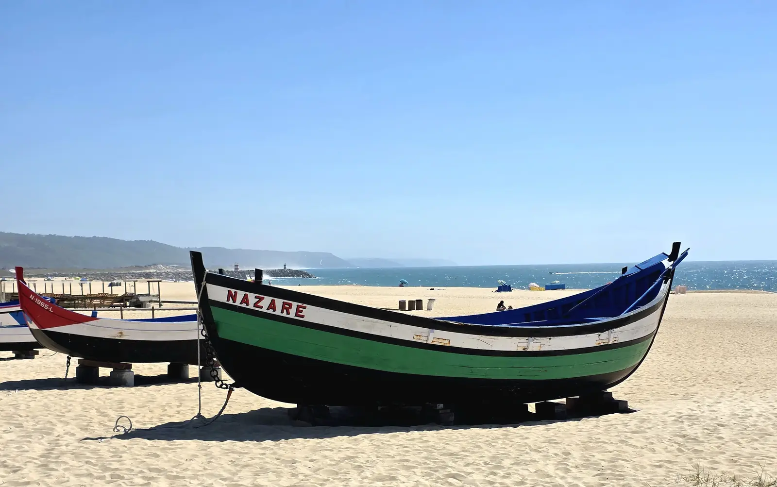 A traditional painted fishing boat resting on the sand at Nazaré