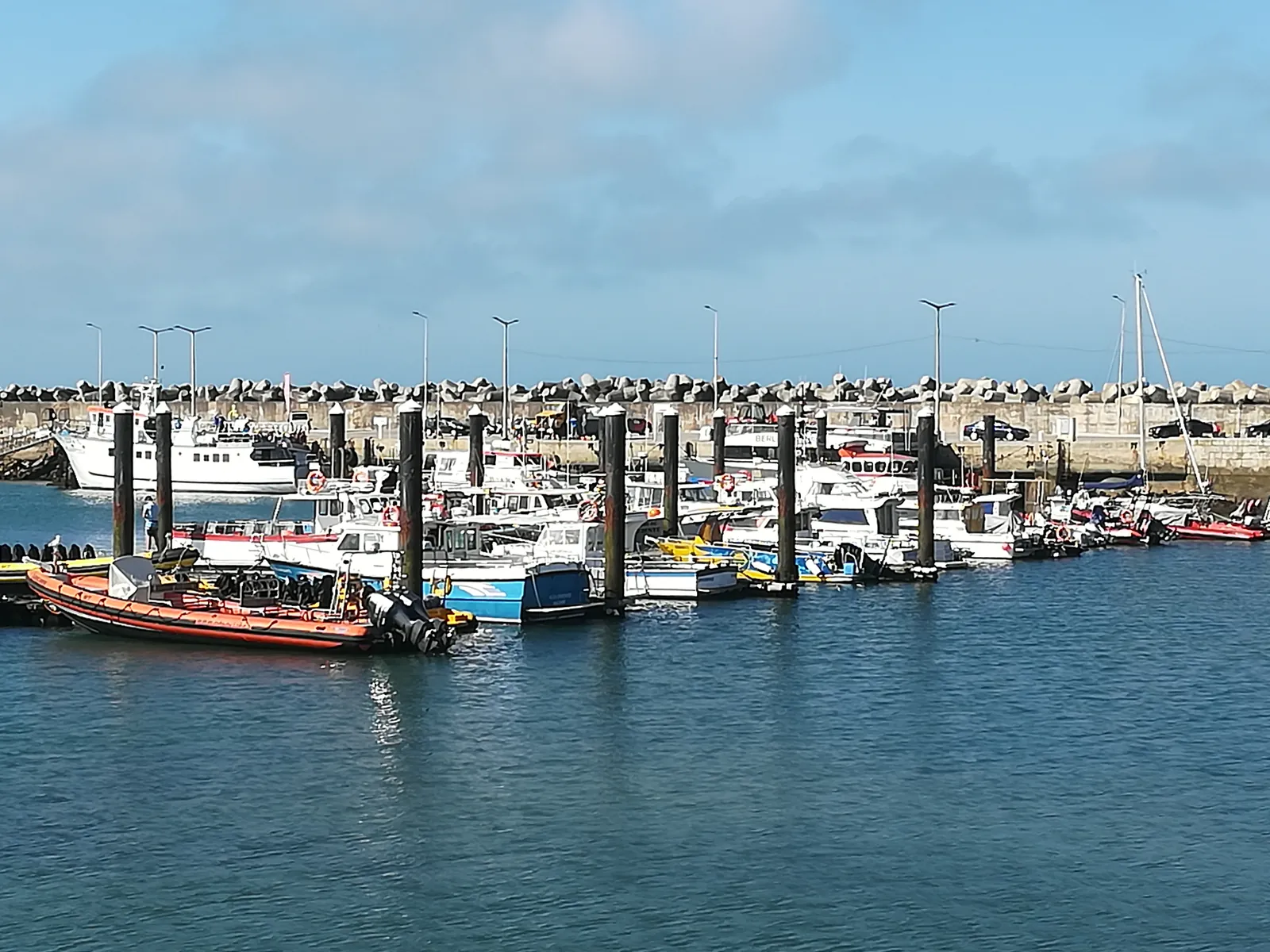 Fishing and leisure boats moored at the pontoons of Peniche harbour beneath the breakwater