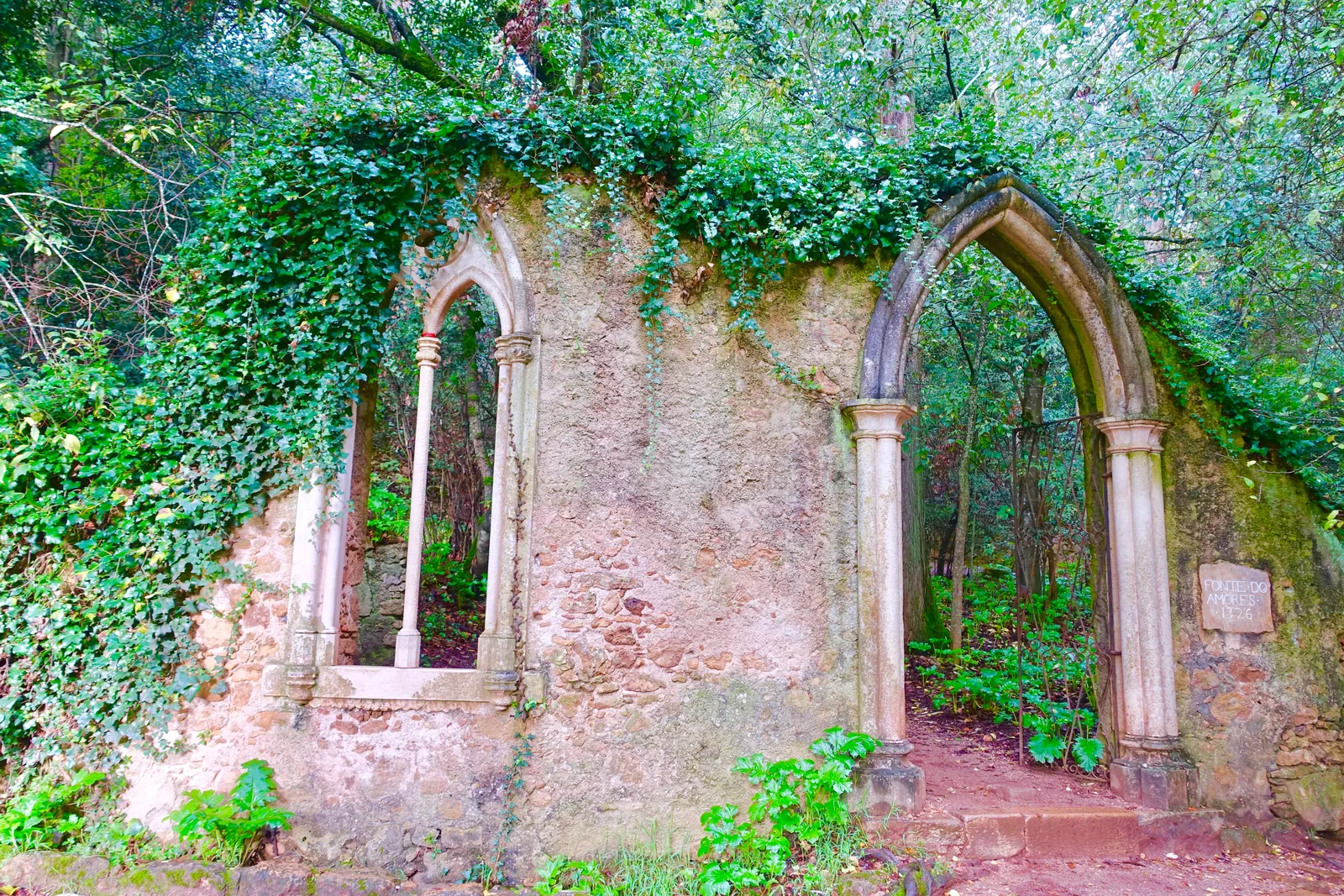 Ivy-covered neo-Gothic arches at the Fonte dos Amores in the wooded gardens of Quinta das Lágrimas, Coimbra