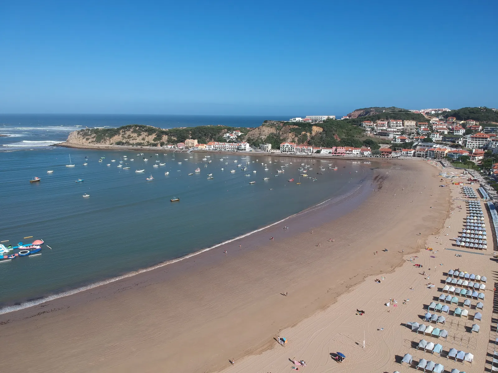 Aerial view of the curved, shell-shaped bay of São Martinho do Porto with moored boats and the sandy beach